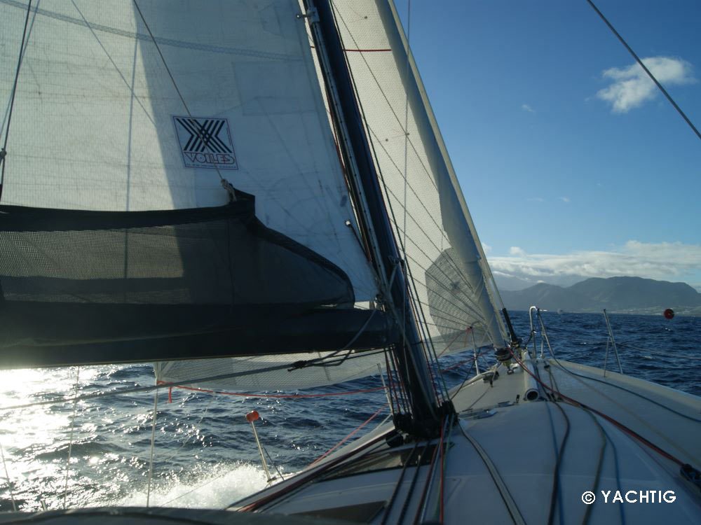 Voilier sous génois en contre jour en approche d'une isle