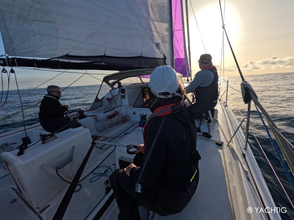 Barreur et équipiers sous spi sur un voilier pogo 40, à l'aube