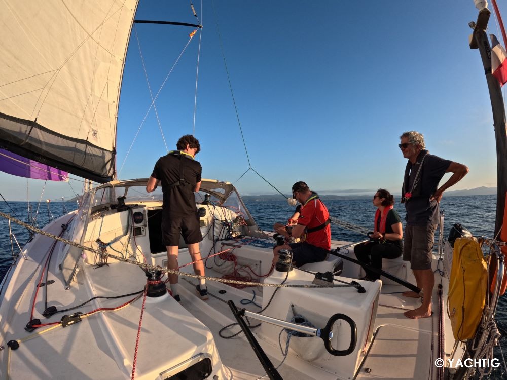 Équipage et skipper dans le cockpit du pogo 40 sous spi, fin de journée